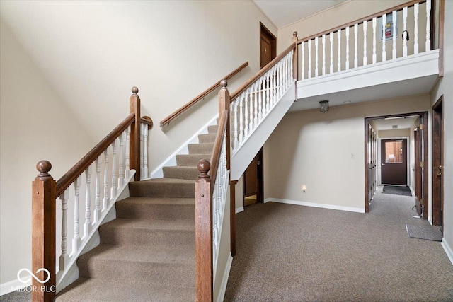 stairway with a high ceiling and carpet floors