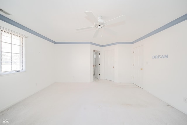 carpeted empty room with crown molding and ceiling fan