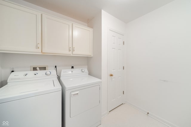 clothes washing area featuring separate washer and dryer and cabinets