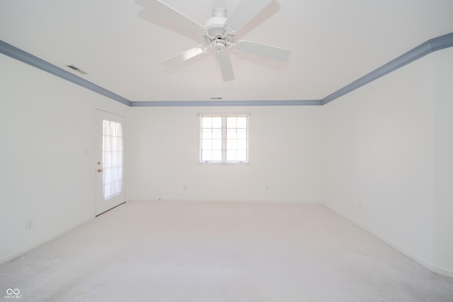 empty room featuring crown molding, light colored carpet, and ceiling fan