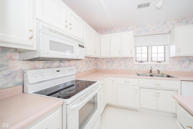 kitchen featuring sink, white appliances, and white cabinets