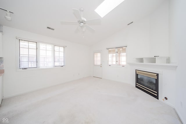 unfurnished living room with light colored carpet, plenty of natural light, and lofted ceiling with skylight