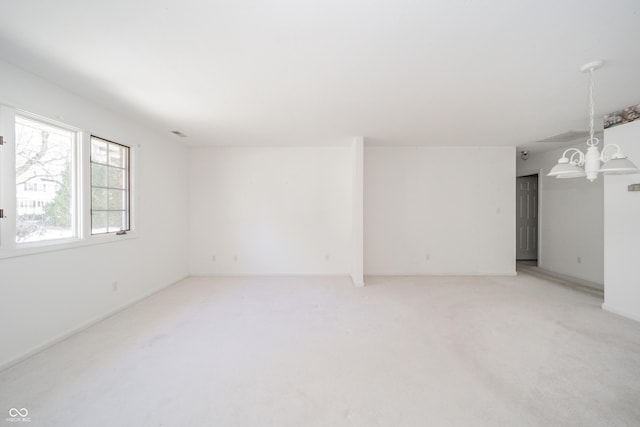 unfurnished room with light colored carpet and a notable chandelier