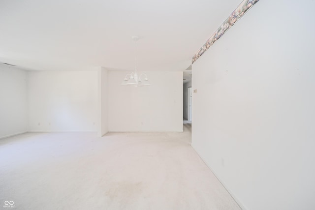 carpeted empty room with a chandelier