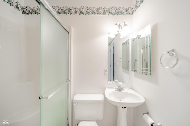 bathroom featuring a shower with door and toilet