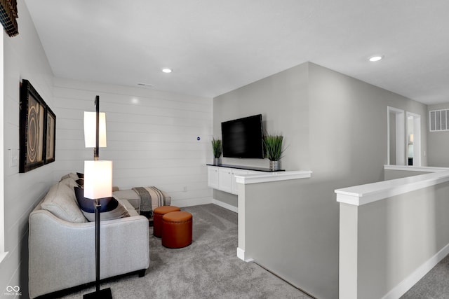 carpeted living room featuring wood walls