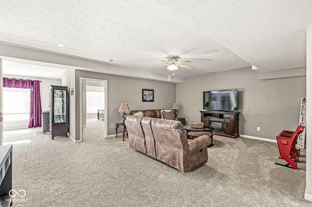 living room featuring a textured ceiling, carpet floors, and ceiling fan