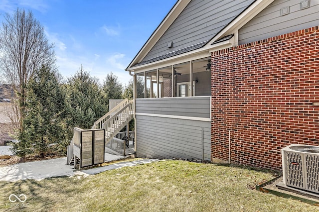 view of home's exterior featuring a sunroom, a yard, central AC unit, and ceiling fan