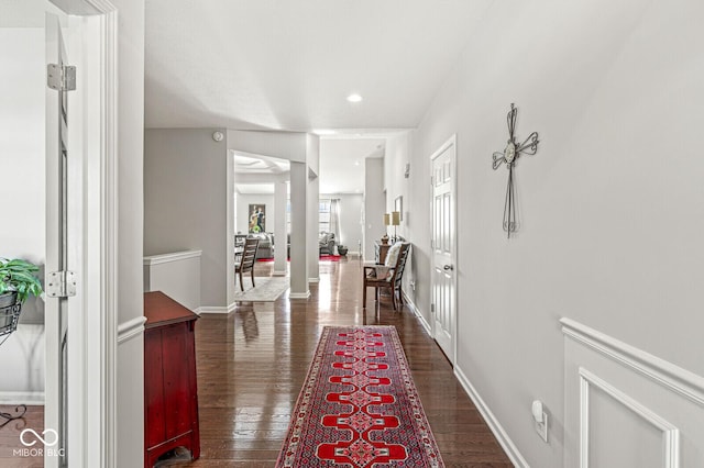 hallway with dark wood-type flooring and decorative columns