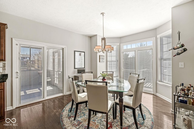 dining room featuring dark wood-type flooring, a notable chandelier, and a textured ceiling