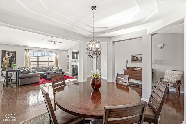 dining space with dark hardwood / wood-style floors, ceiling fan, and a tray ceiling