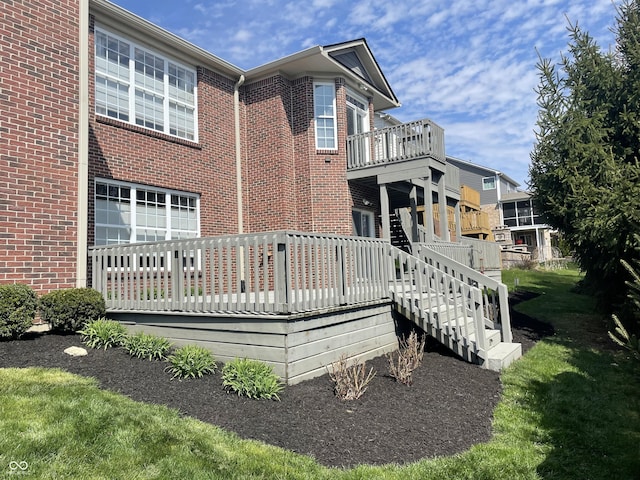 back of property featuring a wooden deck and a lawn