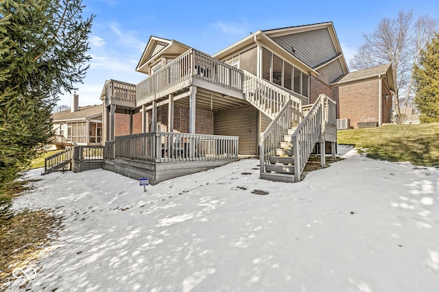 snow covered property with a wooden deck and a sunroom