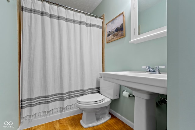 bathroom featuring wood-type flooring, shower / bathtub combination with curtain, a textured ceiling, and toilet