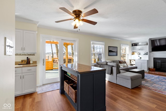 kitchen with a textured ceiling, dark hardwood / wood-style floors, white cabinets, and a center island