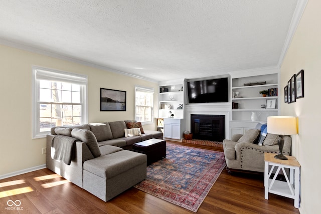 living room with crown molding, dark wood-type flooring, a textured ceiling, and built in shelves