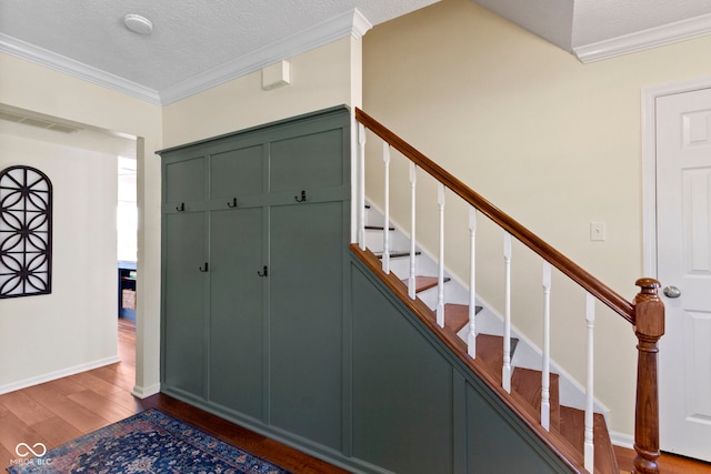 entryway featuring crown molding, wood-type flooring, and a textured ceiling