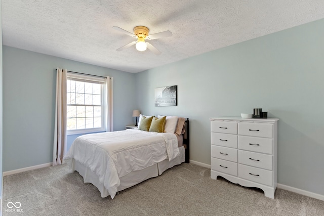 bedroom featuring ceiling fan, light colored carpet, and a textured ceiling