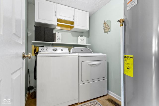 laundry area featuring independent washer and dryer, cabinets, water heater, and a textured ceiling