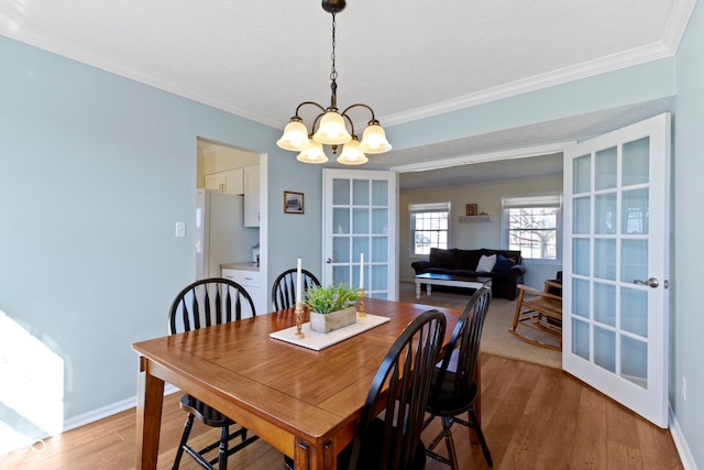 dining area with crown molding, wood-type flooring, and a chandelier