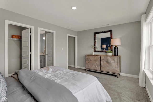 bedroom with multiple windows, connected bathroom, light carpet, and a closet