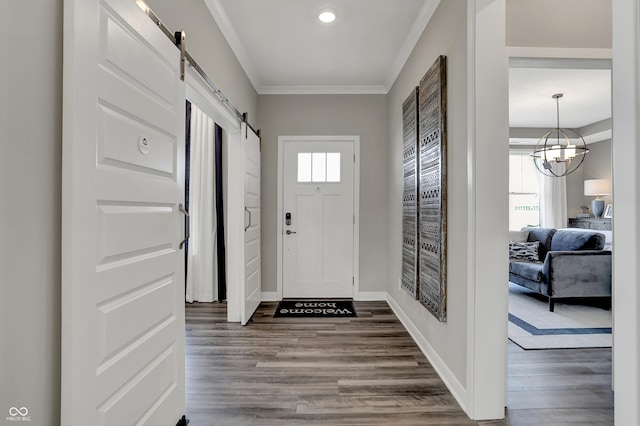 foyer entrance with ornamental molding, a barn door, and hardwood / wood-style floors