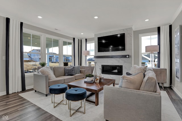 living room featuring crown molding, a high end fireplace, and light wood-type flooring