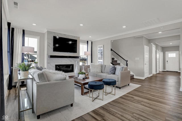 living room with wood-type flooring, crown molding, and a high end fireplace