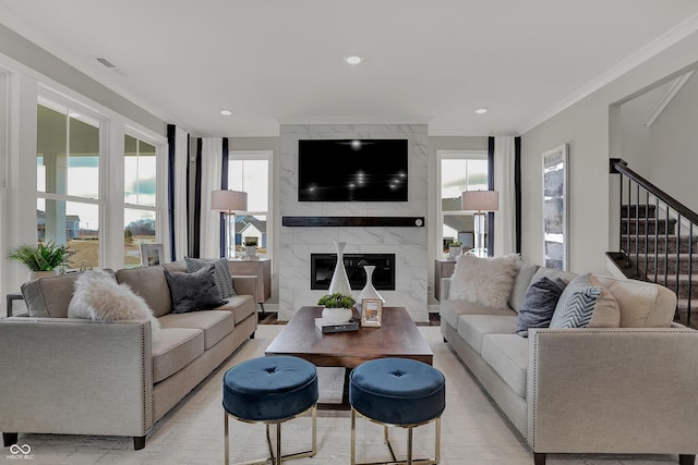 living room with ornamental molding, a wealth of natural light, a high end fireplace, and light hardwood / wood-style floors