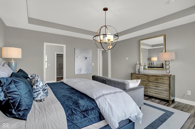 bedroom featuring a tray ceiling, dark wood-type flooring, and a chandelier