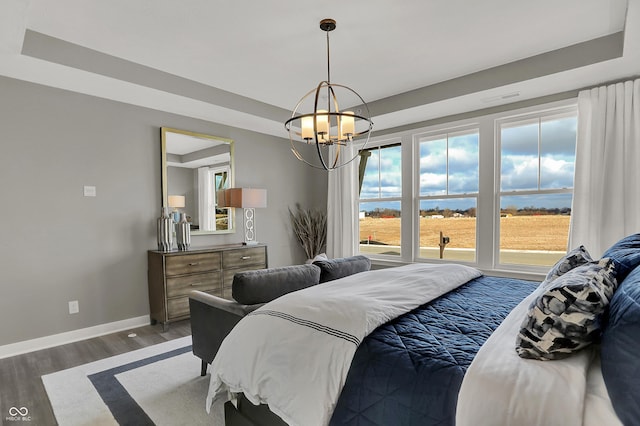 bedroom with dark hardwood / wood-style floors, a raised ceiling, and a notable chandelier