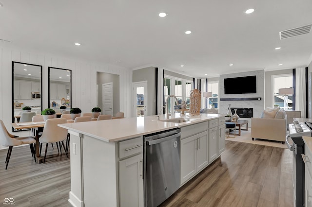 kitchen featuring a high end fireplace, stainless steel appliances, an island with sink, and white cabinets