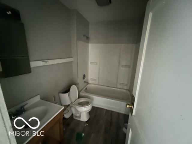 full bathroom featuring hardwood / wood-style flooring, vanity, washtub / shower combination, and toilet