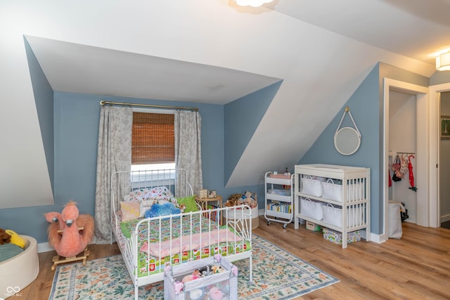 bedroom with vaulted ceiling and light wood-type flooring