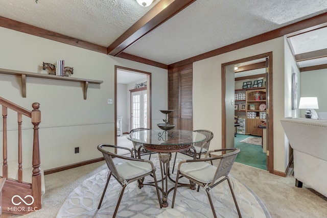 dining room featuring beamed ceiling, light carpet, and a textured ceiling