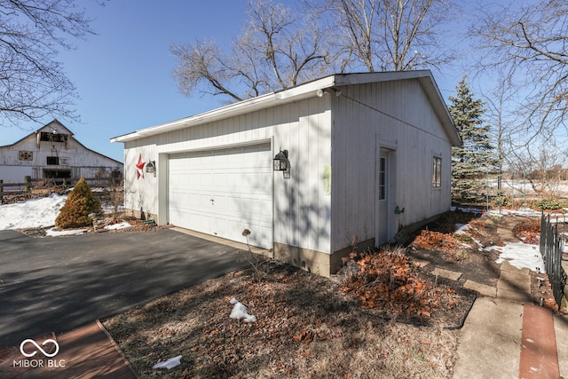 snow covered property featuring a garage and an outbuilding