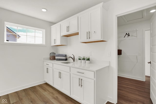 kitchen with hardwood / wood-style flooring, sink, and white cabinets