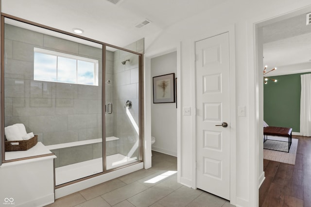 bathroom featuring hardwood / wood-style flooring, a shower with shower door, and toilet