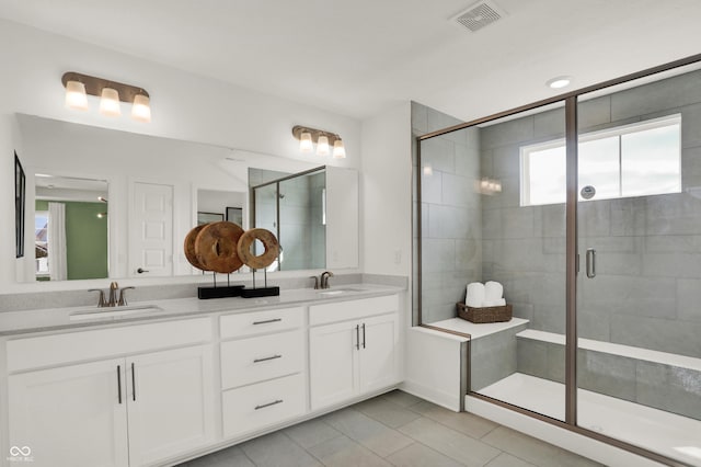 bathroom with a shower with door, vanity, and tile patterned floors