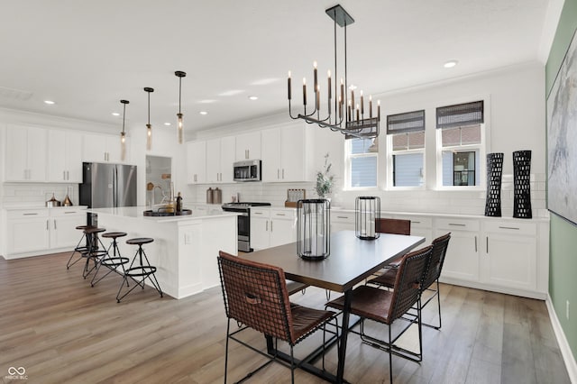 dining space with crown molding, sink, and light hardwood / wood-style flooring