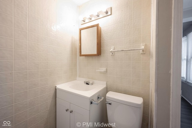 bathroom with vanity, tile walls, and toilet