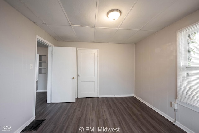 unfurnished room featuring a paneled ceiling and dark hardwood / wood-style floors