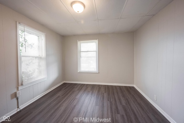 empty room featuring dark wood-type flooring and a paneled ceiling