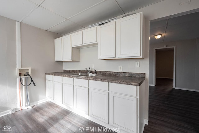 kitchen featuring hardwood / wood-style flooring, white cabinetry, sink, and a paneled ceiling