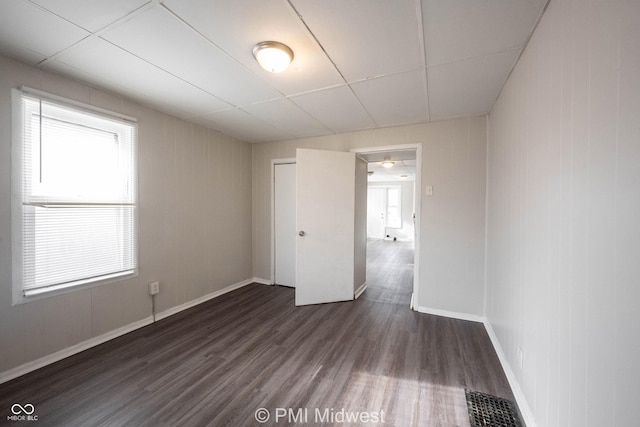 empty room with dark hardwood / wood-style flooring and a healthy amount of sunlight