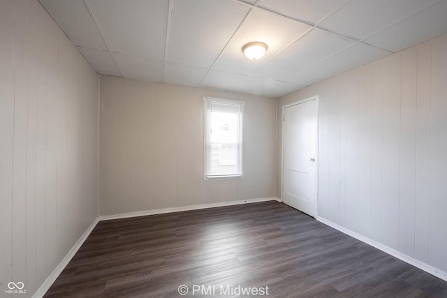 empty room with a paneled ceiling and dark hardwood / wood-style floors