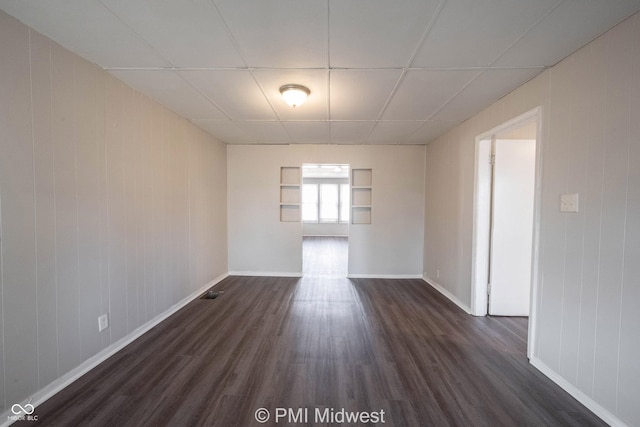 empty room featuring dark wood-type flooring and a paneled ceiling