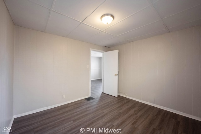 unfurnished room featuring a paneled ceiling and dark hardwood / wood-style floors