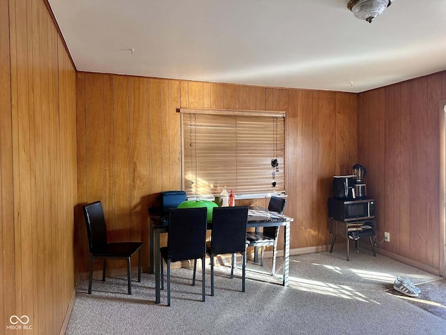 dining room featuring light carpet and wood walls