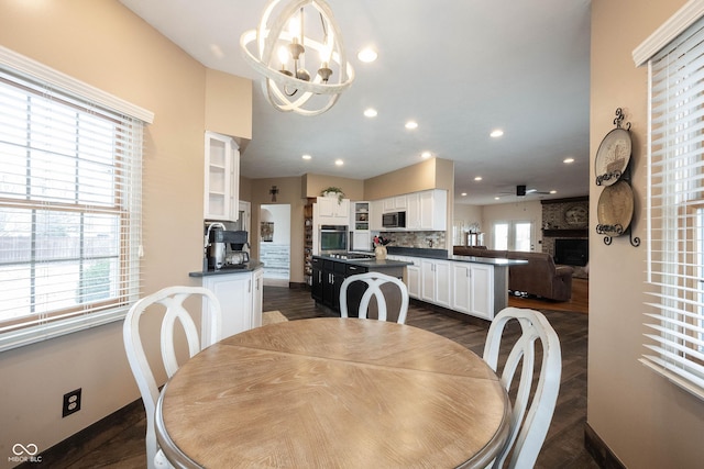 dining room featuring ceiling fan with notable chandelier and dark wood-type flooring